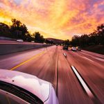 Auto rijdt met snelheid over snelweg tijdens praktijkexamen rijbewijs bij zonsondergang